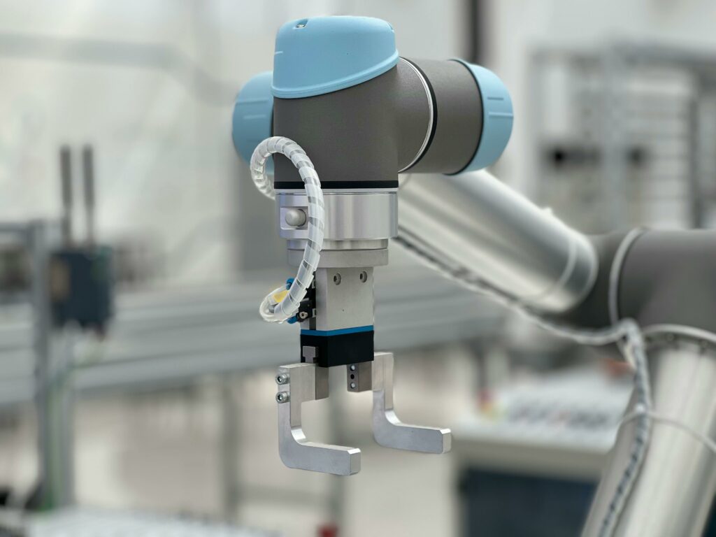 Robotic arm gripper in an industrial manufacturing facility, representing Chronos's mission of machine-anchored operational truth
