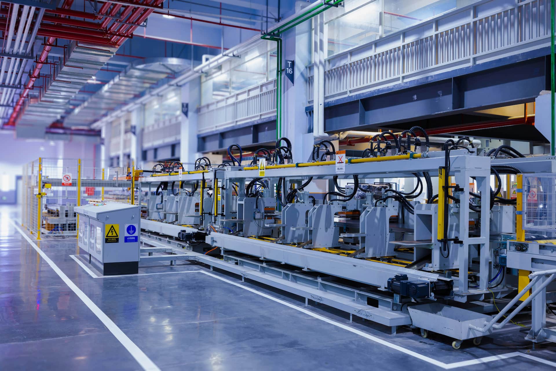 Industrial robotic arm and wiring panel on a manufacturing floor, representing Industry 4.0 and machine-first architecture